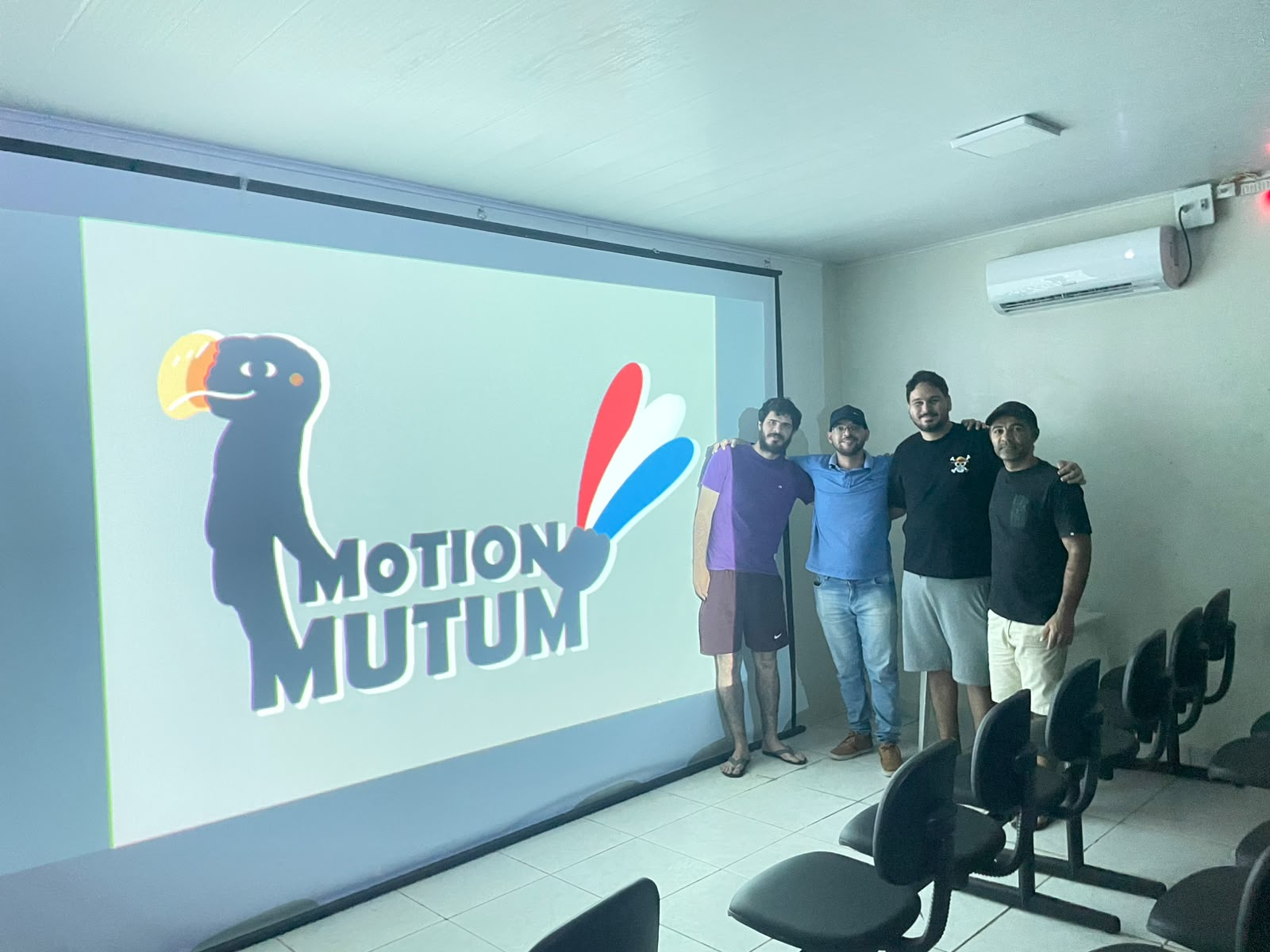 Equipe da Motion Mutum reunida em frente ao logo do estúdio projetado